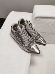 Pair of silver sneakers on a white textured surface