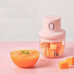 Pink handheld blender with a bowl of orange puree on a pink background