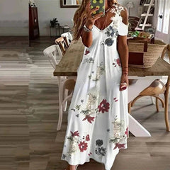 Woman wearing a white floral dress in a room with wooden floors and furniture.