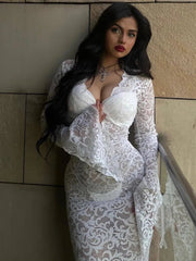 Woman wearing an elegant white lace maxi dress with a V-neck and long sleeves, featuring hollow out detailing.