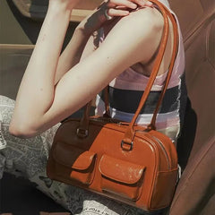 Person holding an orange handbag inside a vehicle