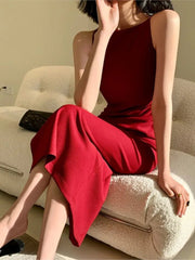 Woman in a red dress sitting on a beige couch.