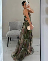 Woman taking a mirror selfie wearing a floral dress in a room with a chair and white walls.