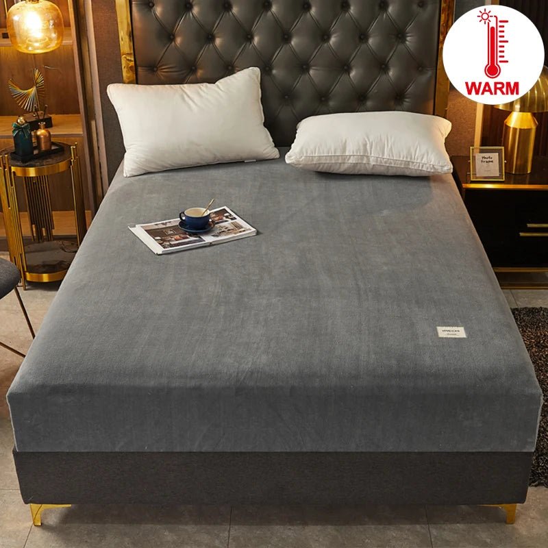 Gray mattress cover on a bed with pillows and a magazine, in a bedroom setting.