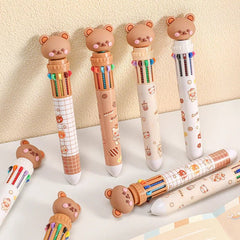Set of cute bear-shaped pens with colorful designs on a light surface.