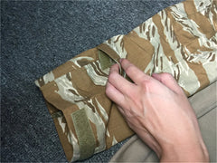Hand folding a camouflage-patterned blanket on a textured surface