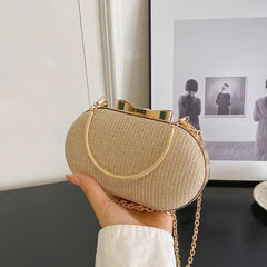 Hand holding a gold woven handbag with a chain strap against a neutral background