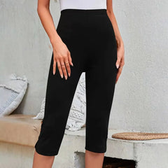 Person wearing black capri pants against a neutral background