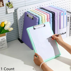Person using a green clipboard with a pen, surrounded by colorful clipboards on a pegboard.