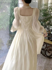 Woman wearing a white vintage-style dress with puffed sleeves in an indoor setting.