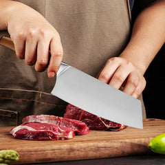 Person cutting raw meat on a wooden board with a large knife.