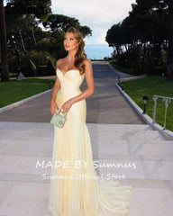 Woman in a yellow evening gown standing on steps with a scenic background, featuring 'Made by Sumnus' branding.