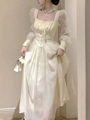 Woman wearing a light-colored dress with sheer sleeves in an indoor setting