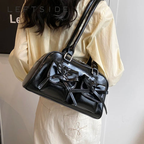 Person wearing a black leather handbag on a plain background