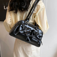 Person wearing a black leather handbag on a plain background