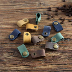 Assorted leather straps with metal clasps on a wooden surface with coffee beans.