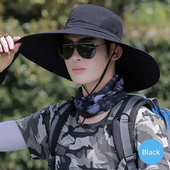 Person wearing a black wide-brimmed hat, sunglasses, camouflage shirt, and backpack outdoors.