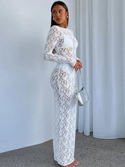 Woman wearing a white lace dress holding a silver handbag against a plain background