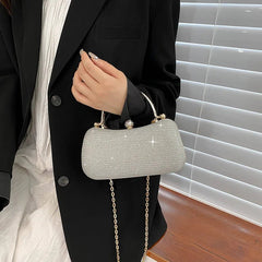 Person holding a silver clutch with a chain strap against a neutral background