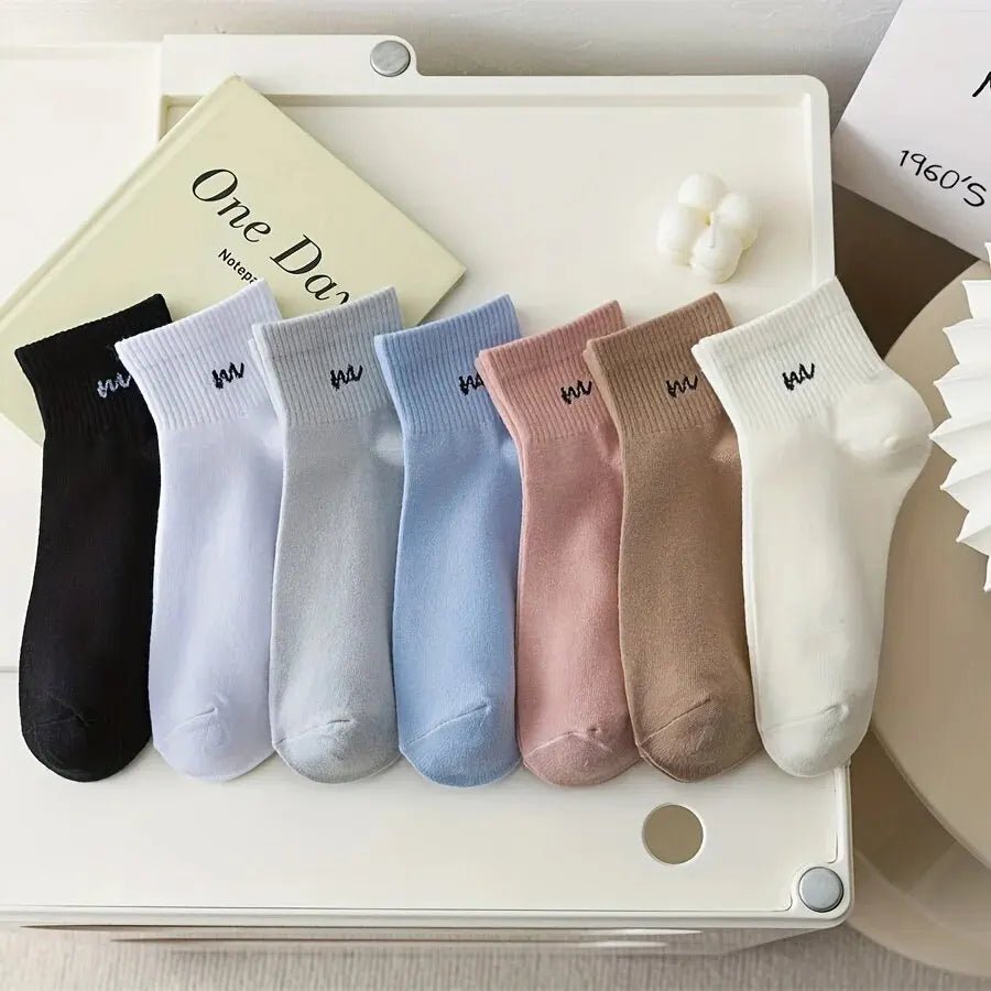 Set of colorful socks arranged on a white surface with a book in the background.