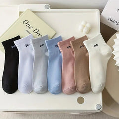 Set of colorful socks arranged on a white surface with a book in the background.