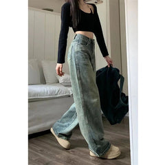 Person wearing light blue jeans and a black top in a room with a couch.