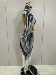 Mannequin wearing a zebra-striped dress with fringe details against a white wall.