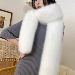 Person wearing a white fur stole over a gray sweater in an indoor setting