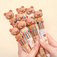 Set of colorful pens with bear-shaped caps held by a hand on a beige background