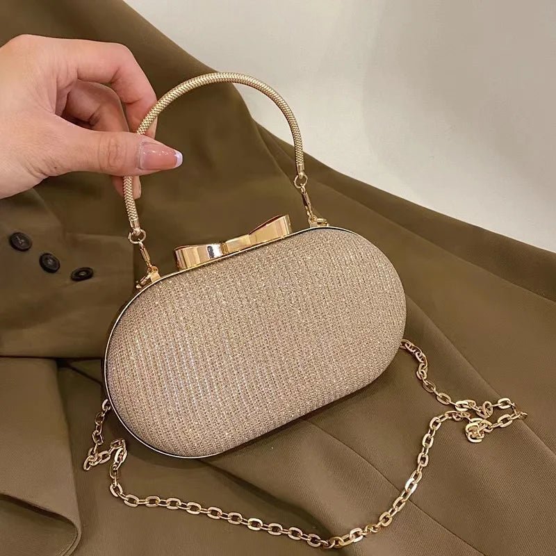Beige handbag with gold chain strap held by a hand on a beige background