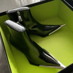 Black high-heeled shoes with silver accents in a green shoebox.