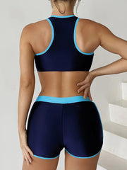 Person wearing a navy sports bra and shorts with light blue trim on a white background
