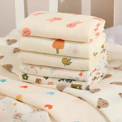 Stack of baby blankets with colorful patterns on a white surface