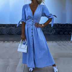 Woman wearing a blue dress with a white handbag in an outdoor setting