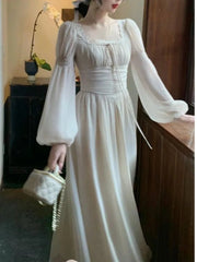 Woman wearing a white dress with long sleeves in an indoor setting.