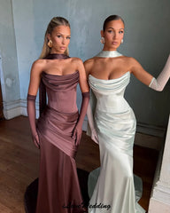 Two women in elegant evening gowns standing side by side indoors.