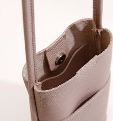 Close-up of a beige handbag with a visible zipper and strap.