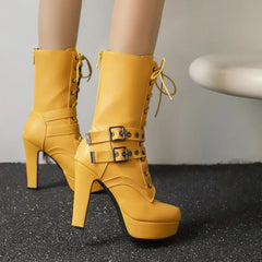 Yellow high-heeled boots with platform sole on a gray background
