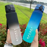 Two gradient water bottles held in hands with a natural background