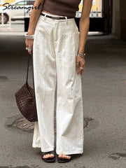 Person wearing white wide-leg pants on a street.