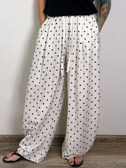 White pants with black polka dots worn by a person against a plain background