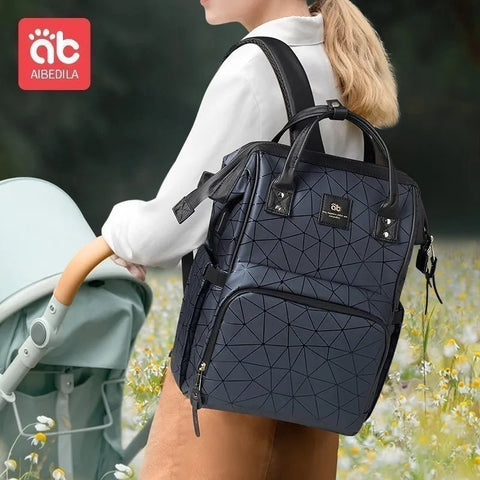 Person holding a black geometric-patterned backpack with a stroller in a field