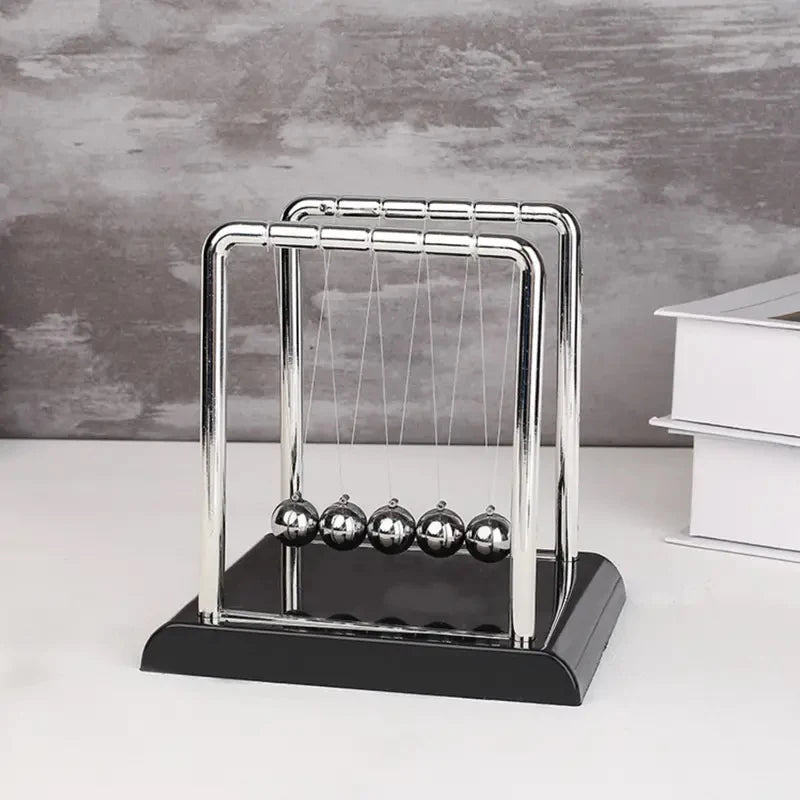 Newton's cradle on a white surface with a gray background