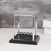 Newton's cradle on a white surface with a gray background