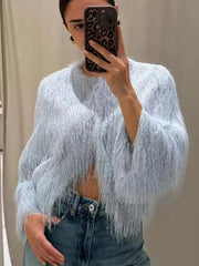 Person wearing a light blue fringed sweater and denim jeans, taking a mirror selfie.