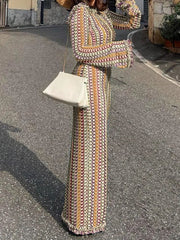 Person wearing a colorful patterned dress holding a white handbag on a street.