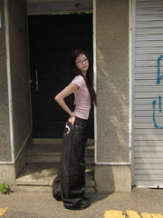 Person wearing a pink shirt and black pants standing in a doorway.