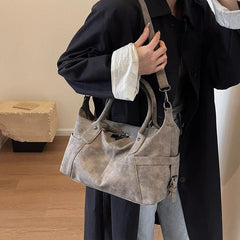 Person holding a gray handbag indoors