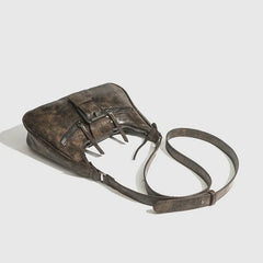Brown leather bag with a strap on a light gray background