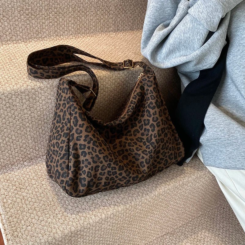 Leopard print handbag on a textured surface with a gray garment in the background